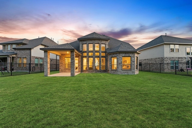 back house at dusk featuring a lawn