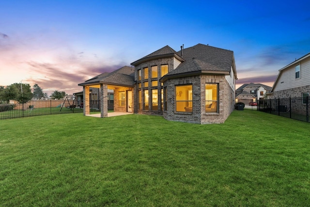 back house at dusk with a lawn and a patio area