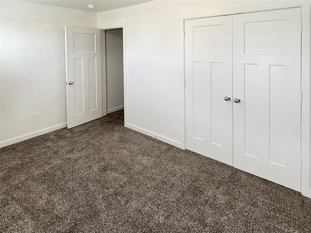 unfurnished bedroom with dark colored carpet and a closet