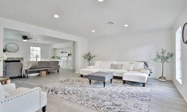 living room featuring light wood-type flooring, a textured ceiling, and ceiling fan