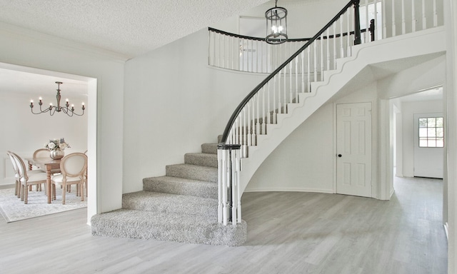 stairs with hardwood / wood-style flooring, a notable chandelier, and a textured ceiling