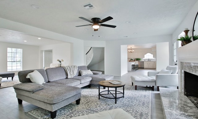 living room featuring ceiling fan with notable chandelier, a fireplace, a textured ceiling, hardwood / wood-style floors, and sink