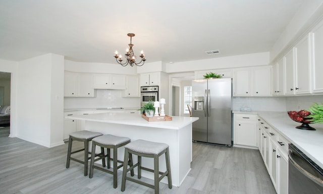 kitchen featuring a kitchen island, white cabinetry, appliances with stainless steel finishes, a breakfast bar area, and light wood-type flooring