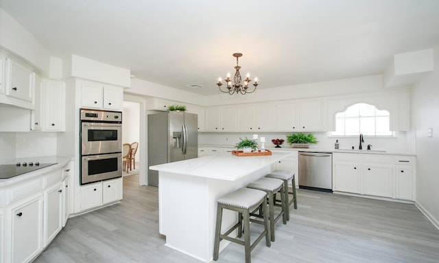 kitchen featuring a center island, sink, white cabinets, an inviting chandelier, and stainless steel appliances