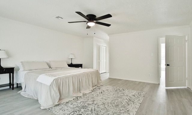 bedroom featuring a textured ceiling, light hardwood / wood-style floors, ornamental molding, and ceiling fan