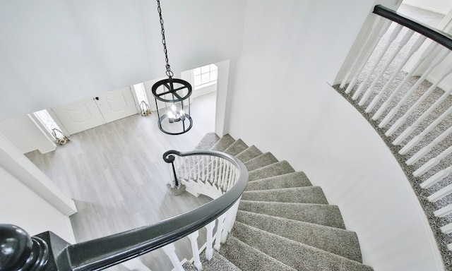 staircase featuring wood-type flooring and a chandelier