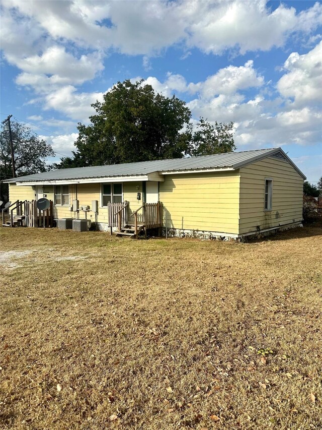 rear view of property featuring a yard and central AC unit