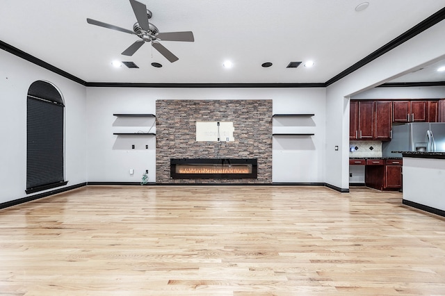 unfurnished living room featuring light wood-type flooring, ceiling fan, a fireplace, and crown molding