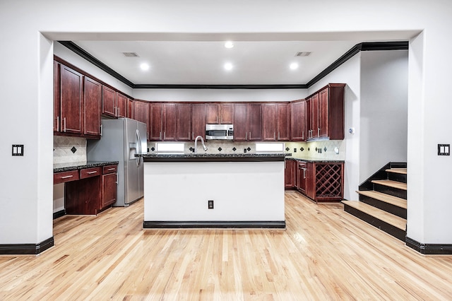 kitchen featuring crown molding, light hardwood / wood-style floors, a kitchen island with sink, and stainless steel appliances