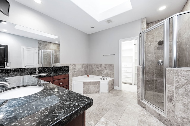 bathroom featuring shower with separate bathtub, vanity, and a skylight