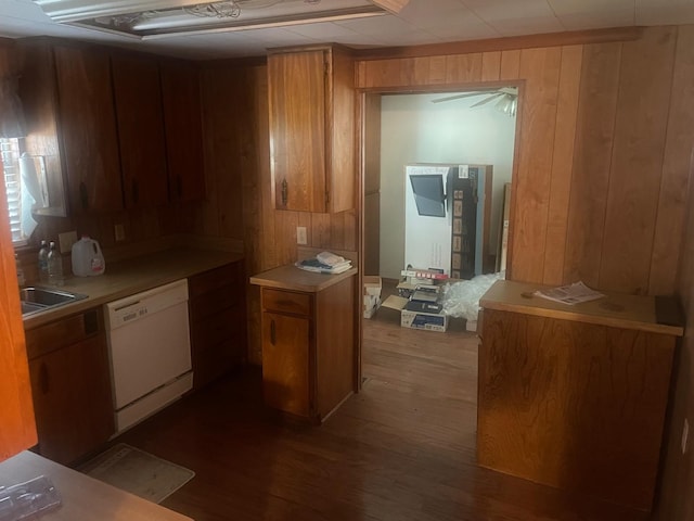 kitchen with dishwasher, wood walls, dark wood-type flooring, and sink