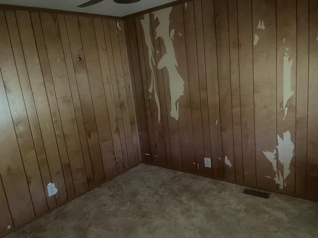 spare room with ceiling fan and wooden walls