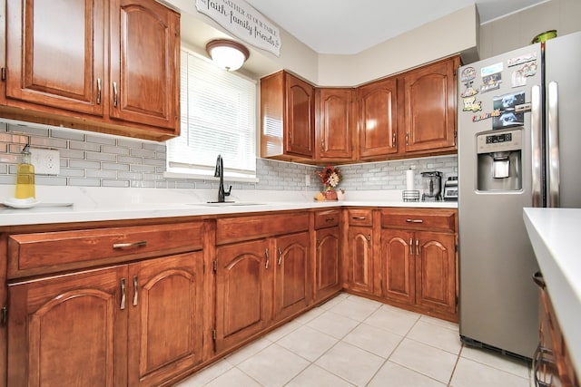 kitchen featuring stainless steel refrigerator with ice dispenser, light tile patterned floors, backsplash, and sink