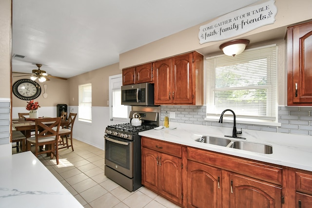 kitchen with backsplash, appliances with stainless steel finishes, sink, and light tile patterned floors