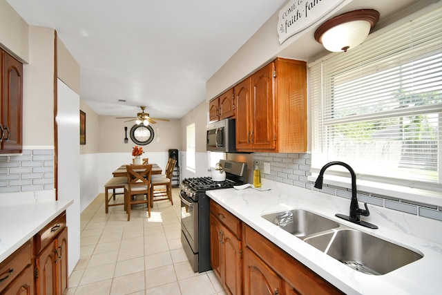 kitchen featuring backsplash, appliances with stainless steel finishes, sink, and light tile patterned floors