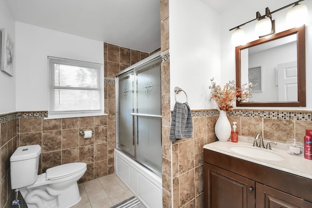 full bathroom featuring tile walls, tile patterned floors, enclosed tub / shower combo, vanity, and toilet