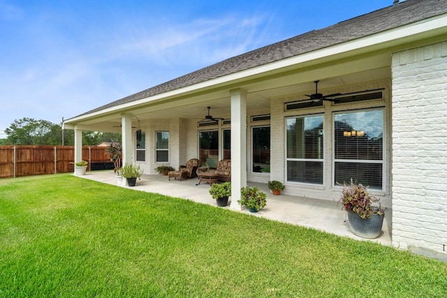 back of house with fence, ceiling fan, a patio area, a lawn, and brick siding