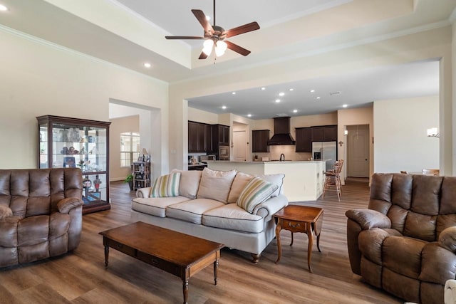living area with recessed lighting, wood finished floors, a ceiling fan, and ornamental molding