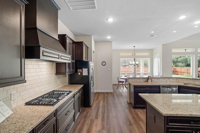 kitchen featuring tasteful backsplash, a chandelier, stainless steel appliances, dark wood finished floors, and visible vents