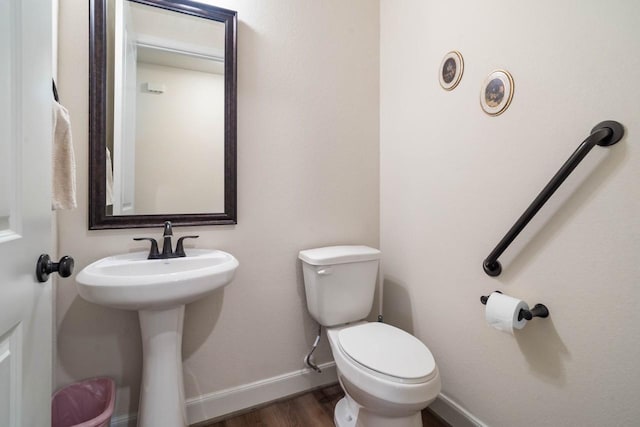 bathroom featuring wood finished floors, toilet, baseboards, and a sink