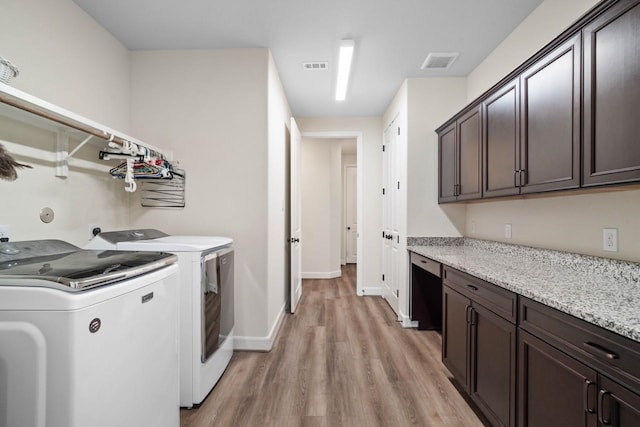 clothes washing area featuring washing machine and clothes dryer, light wood-style floors, cabinet space, baseboards, and visible vents