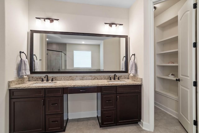 bathroom featuring double vanity, a shower stall, tile patterned flooring, and a sink