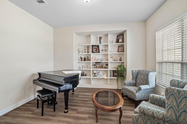 living area featuring baseboards, wood finished floors, visible vents, and plenty of natural light