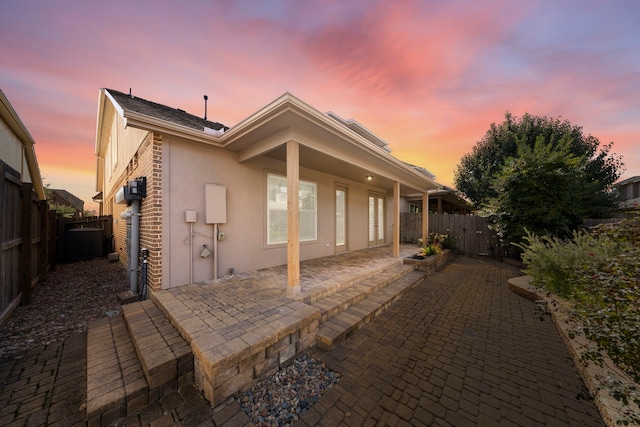 back house at dusk with a patio area