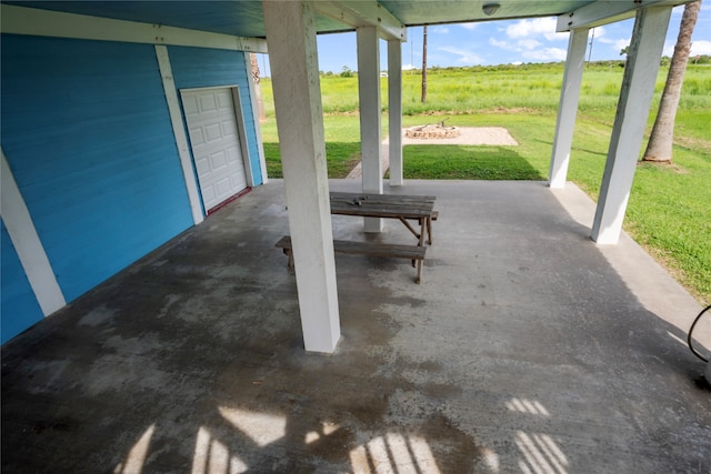 view of patio / terrace featuring a rural view and a garage