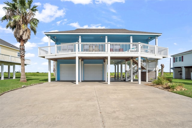 raised beach house featuring a front lawn, a porch, and a garage