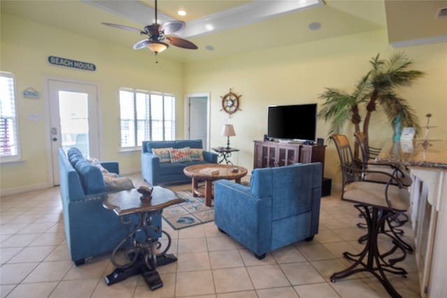 living room featuring ceiling fan, a raised ceiling, and light tile patterned floors