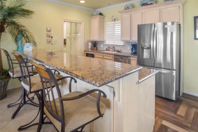 kitchen featuring a breakfast bar area, ornamental molding, appliances with stainless steel finishes, light stone countertops, and dark parquet flooring