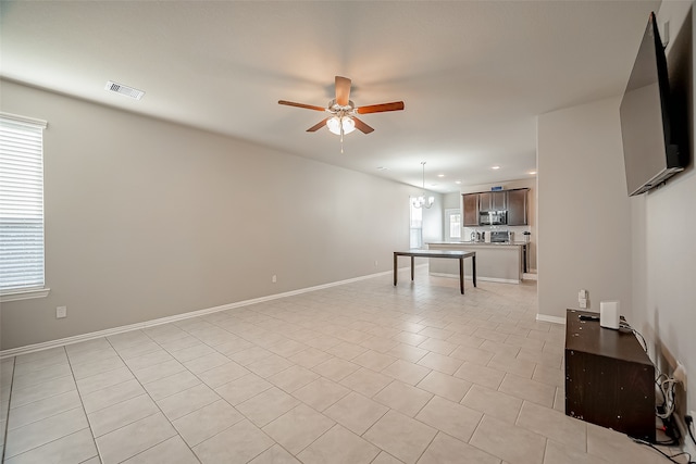 unfurnished living room featuring ceiling fan with notable chandelier and light tile patterned floors