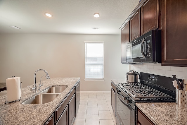 kitchen with light stone counters, tasteful backsplash, black appliances, dark brown cabinets, and sink