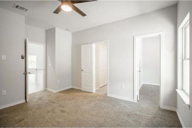 unfurnished bedroom featuring multiple windows, ceiling fan, and light carpet