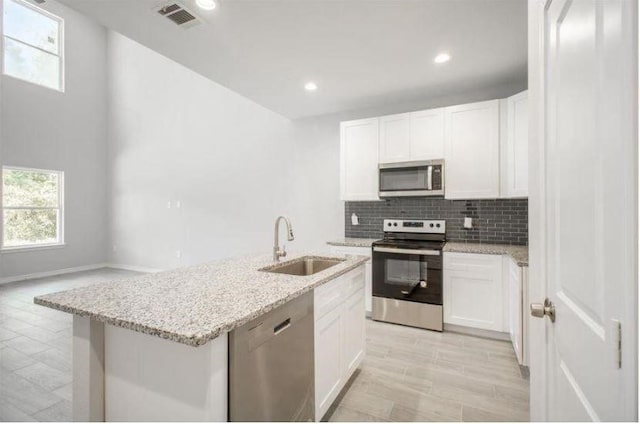 kitchen with a kitchen island with sink, white cabinets, and appliances with stainless steel finishes