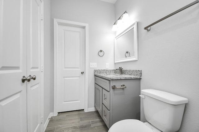 bathroom with hardwood / wood-style floors, vanity, and toilet