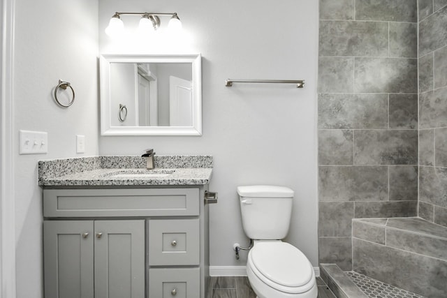 bathroom with tiled shower, vanity, and toilet