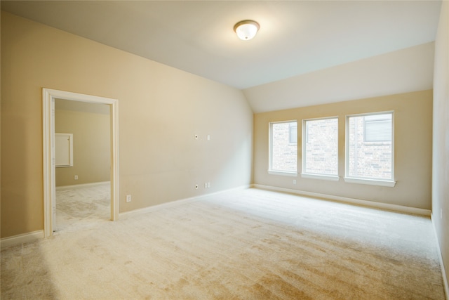 empty room featuring vaulted ceiling and light colored carpet