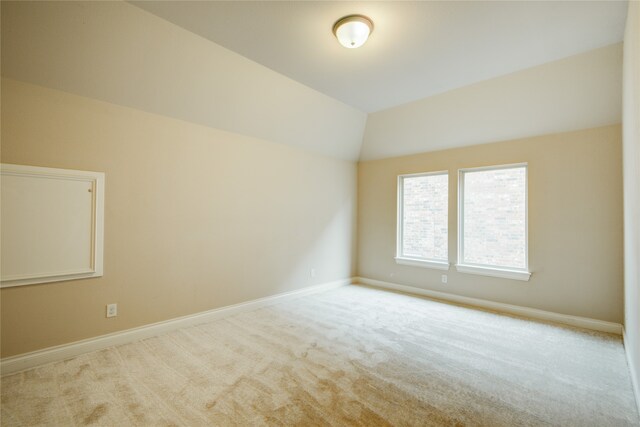 carpeted spare room with lofted ceiling