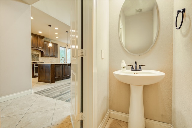 bathroom with tile patterned flooring, sink, and decorative backsplash