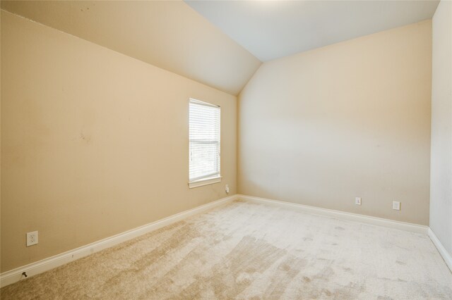 spare room with lofted ceiling and light carpet