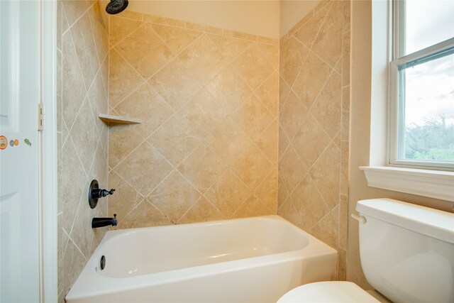 bathroom featuring tiled shower / bath combo and toilet