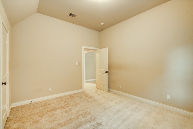 carpeted spare room featuring vaulted ceiling