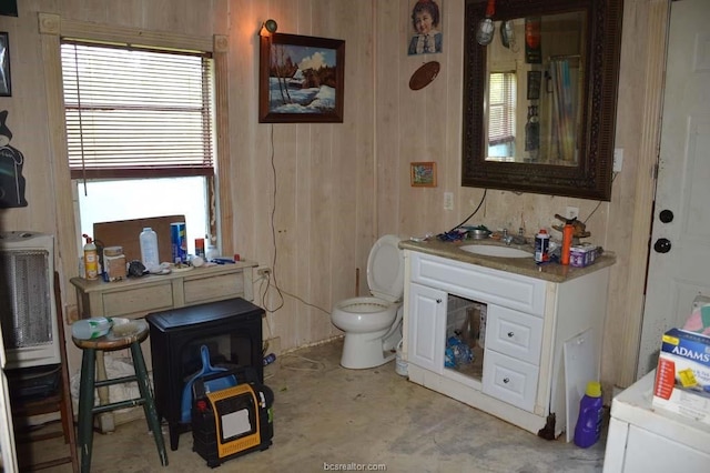 bathroom featuring wooden walls, toilet, and vanity