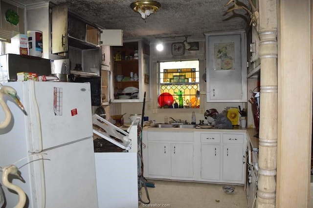 kitchen with white cabinets, white refrigerator, and sink