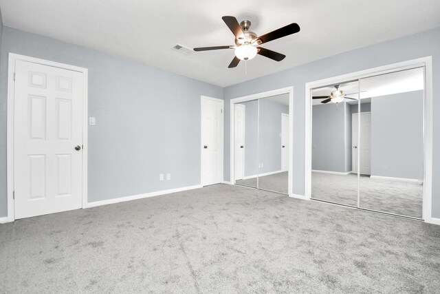 unfurnished bedroom with carpet flooring, two closets, and ceiling fan