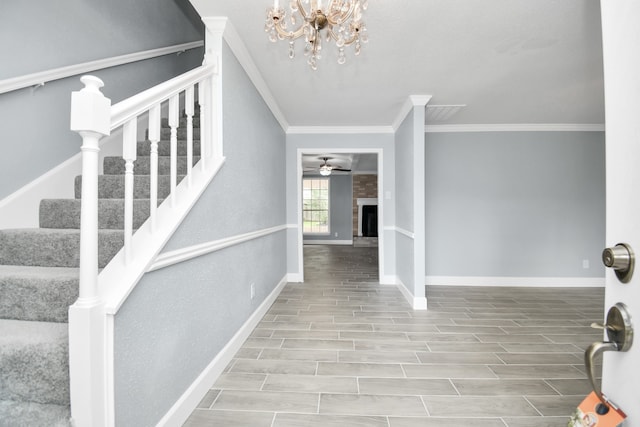 foyer entrance with ceiling fan with notable chandelier, wood-type flooring, and ornamental molding