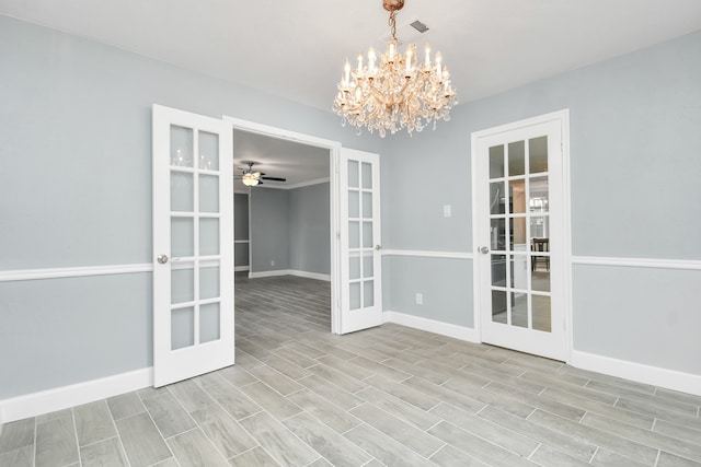 spare room with ceiling fan with notable chandelier, light hardwood / wood-style flooring, and french doors