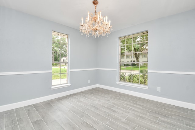 empty room featuring light wood-type flooring, an inviting chandelier, and plenty of natural light